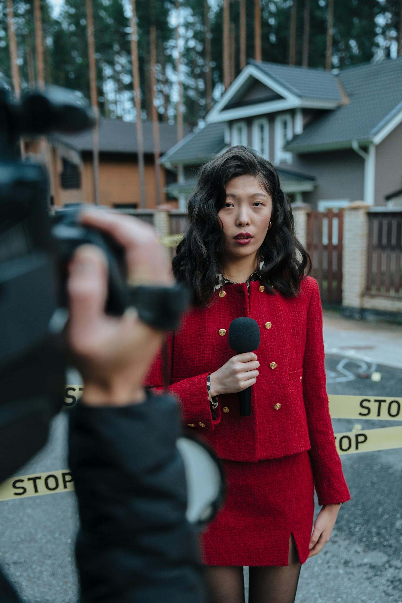 Young reporter holding microphone outdoors at a crime scene press event.